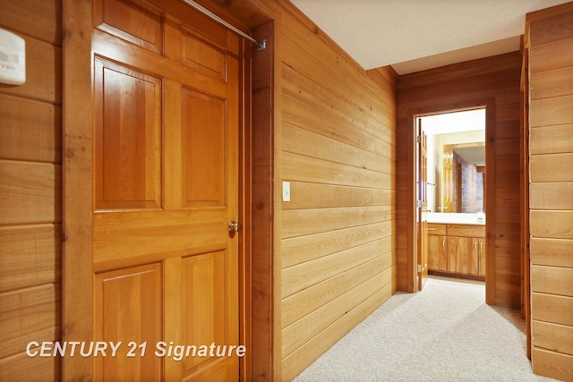 hall featuring light carpet and wooden walls