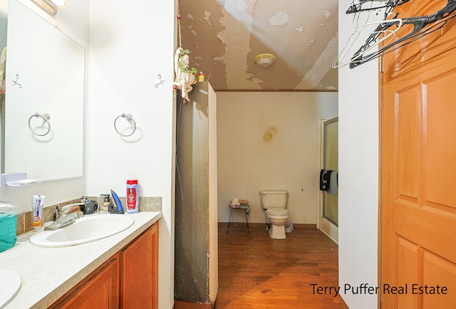 bathroom featuring vanity, toilet, wood-type flooring, and walk in shower