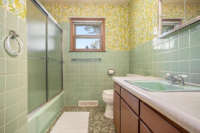 full bathroom featuring tile patterned floors, toilet, enclosed tub / shower combo, and tile walls