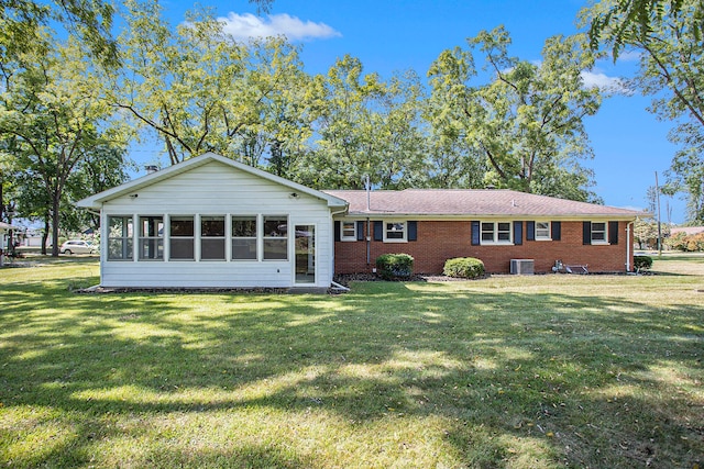 back of property with a lawn, central air condition unit, and a sunroom