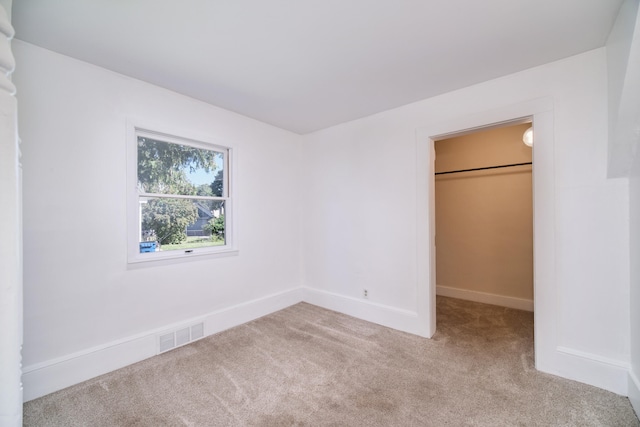 unfurnished bedroom featuring light carpet, a spacious closet, and a closet