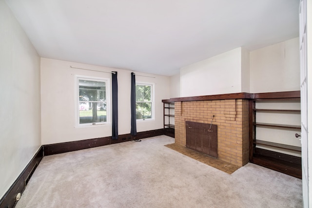 unfurnished living room with light colored carpet and a brick fireplace