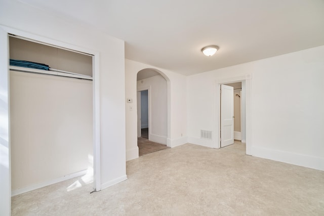 unfurnished bedroom with light carpet and a closet