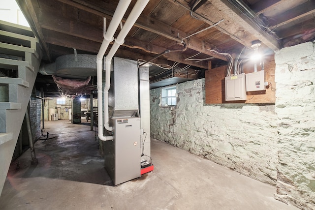 basement featuring electric panel, heating unit, and electric water heater