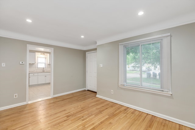 spare room featuring light hardwood / wood-style floors, ornamental molding, and sink