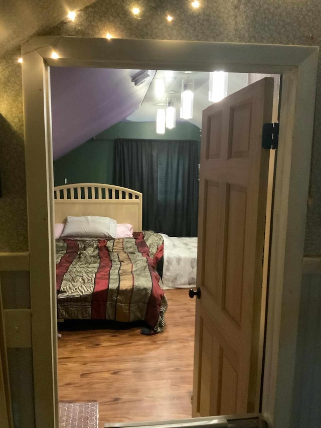 bedroom with hardwood / wood-style floors and lofted ceiling