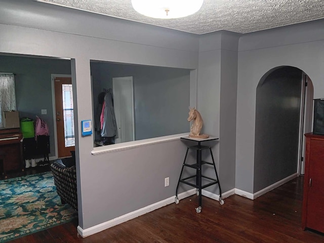 corridor with a textured ceiling and dark hardwood / wood-style floors