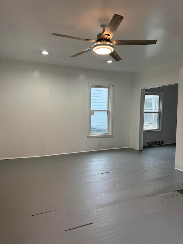 empty room featuring ceiling fan, hardwood / wood-style floors, and a healthy amount of sunlight