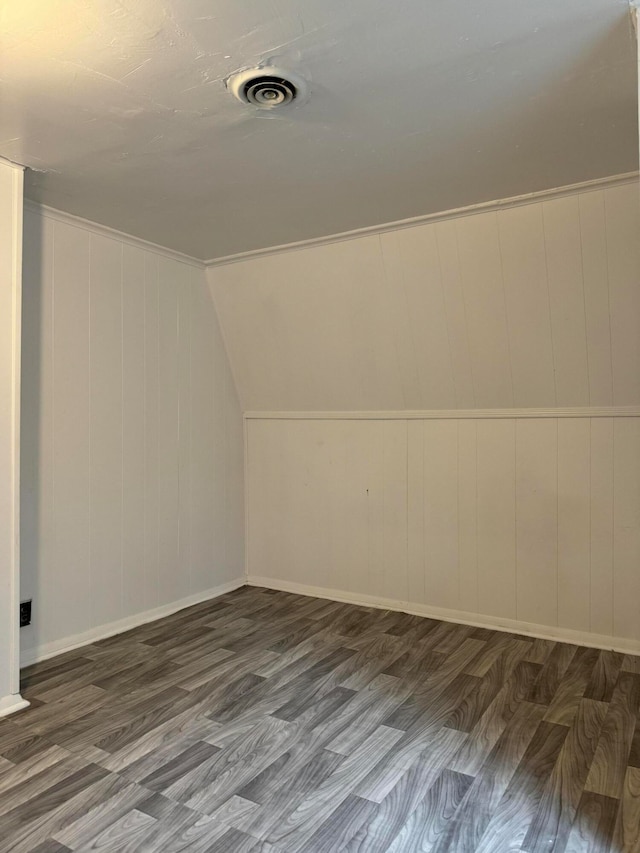 additional living space with wood walls, dark hardwood / wood-style flooring, and lofted ceiling