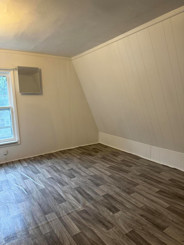 additional living space featuring vaulted ceiling, wooden walls, and dark hardwood / wood-style floors