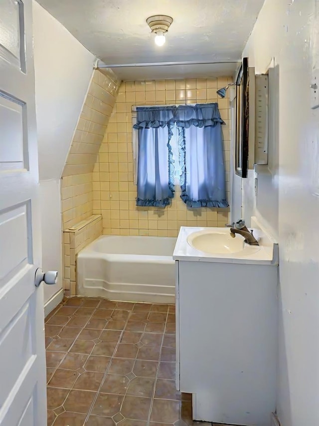 bathroom with tile patterned floors, vanity, tile walls, and tiled shower / bath