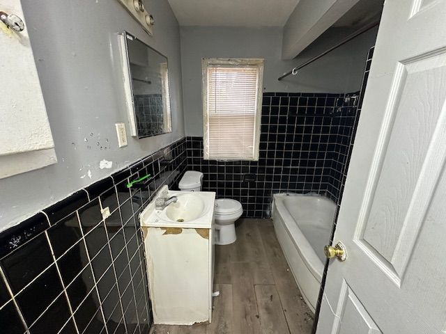 full bathroom with vanity, bathing tub / shower combination, toilet, tile walls, and wood-type flooring