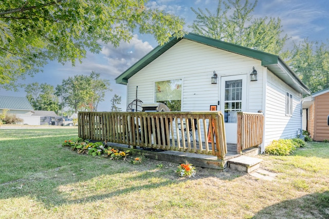 back of property featuring a lawn and a deck