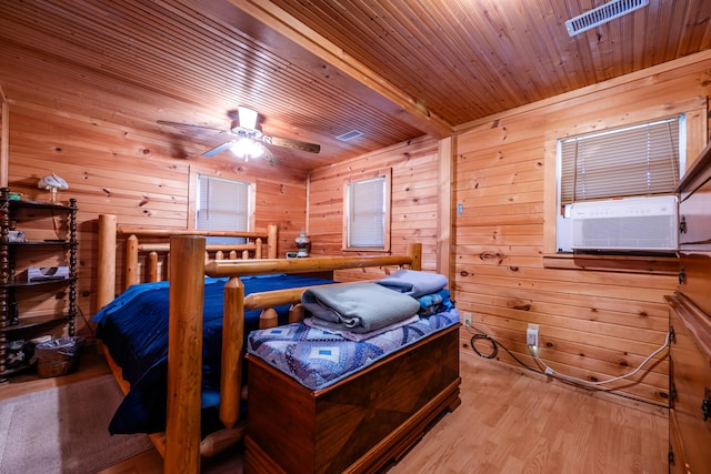 bedroom featuring ceiling fan, wooden ceiling, cooling unit, light hardwood / wood-style floors, and wooden walls