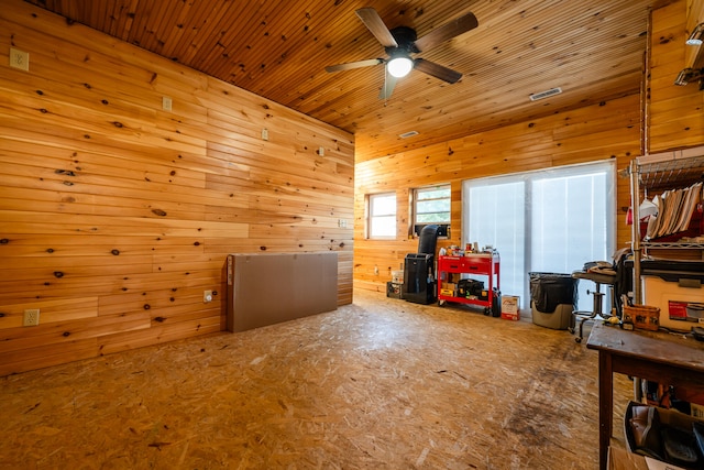 additional living space featuring ceiling fan and wood walls