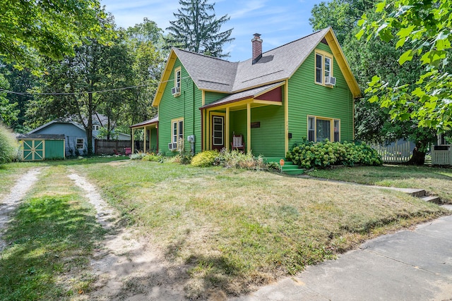 view of front of property featuring a front yard and a shed