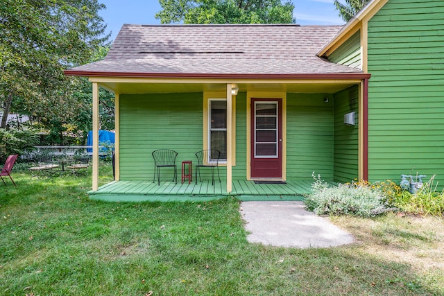 view of exterior entry with covered porch and a lawn