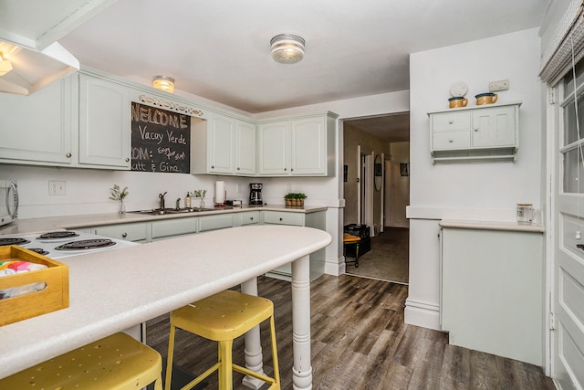 kitchen featuring a kitchen bar, dark hardwood / wood-style flooring, white cabinetry, and sink