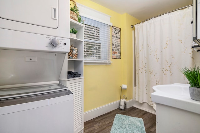 bathroom featuring hardwood / wood-style floors and stacked washer / drying machine