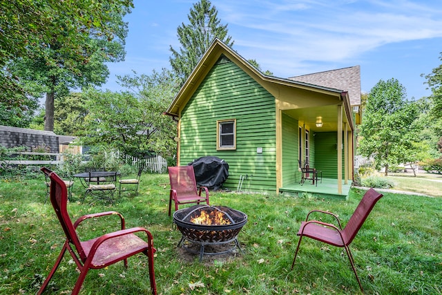 rear view of house featuring a fire pit and a lawn