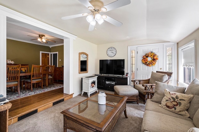 living room featuring a wood stove, ceiling fan, crown molding, hardwood / wood-style floors, and vaulted ceiling