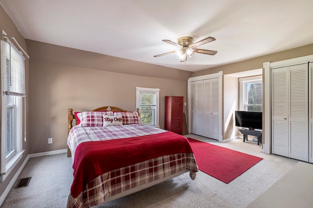 carpeted bedroom with two closets and ceiling fan