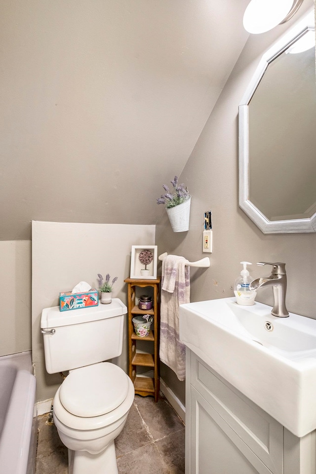 bathroom with vanity, tile patterned floors, vaulted ceiling, toilet, and a tub to relax in