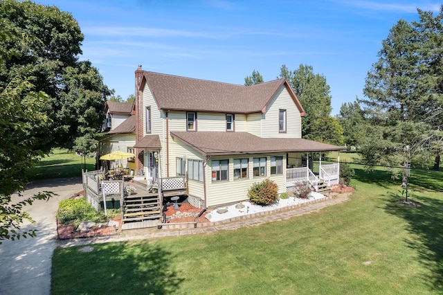 rear view of property with a yard, a porch, and a deck