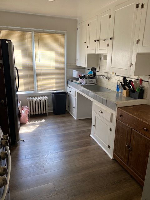5051 Bishop St, Detroit, MI 48224 - kitchen featuring radiator, freestanding refrigerator, white cabinets, dark wood finished floors, and tasteful backsplash