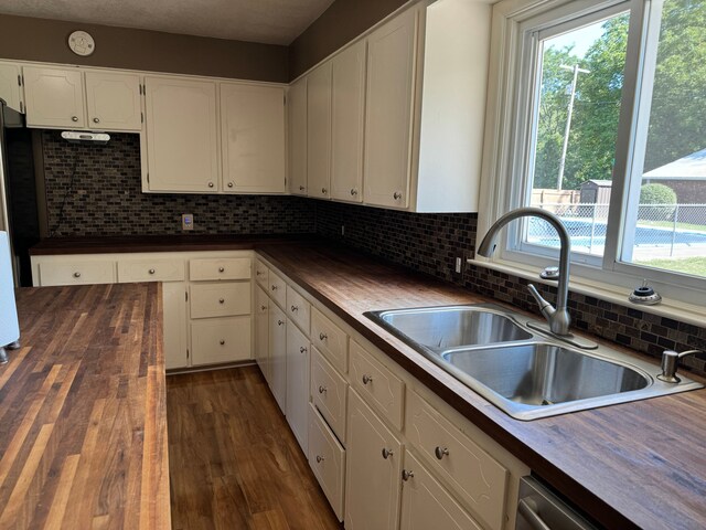2065 S Lapeer Rd, Lapeer, MI 48446 - kitchen with butcher block countertops, a sink, white cabinetry, decorative backsplash, and dark wood-style flooring