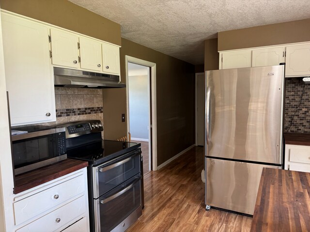 2065 S Lapeer Rd, Lapeer, MI 48446 - kitchen with appliances with stainless steel finishes, under cabinet range hood, backsplash, light wood-type flooring, and white cabinetry