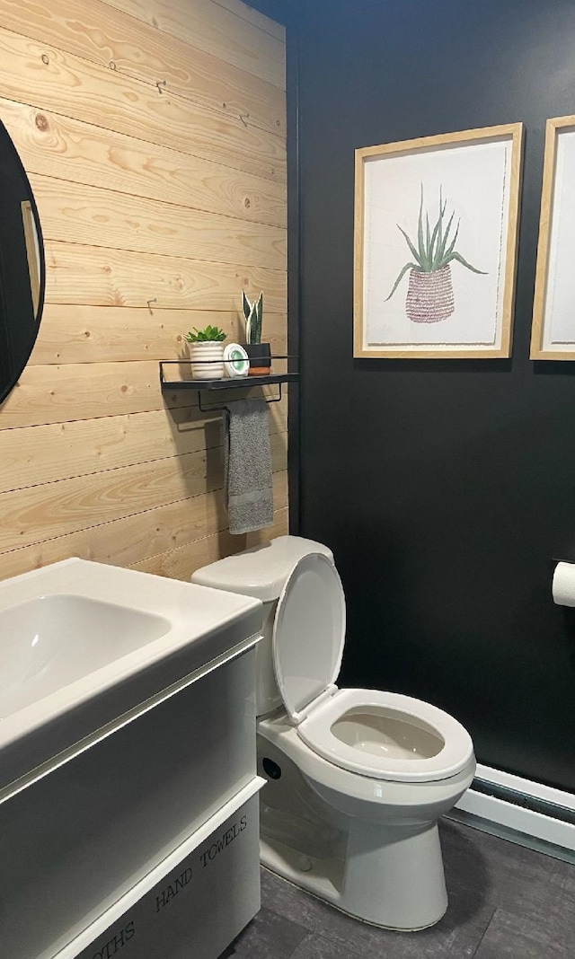 bathroom featuring vanity, wooden walls, tile patterned flooring, toilet, and baseboard heating