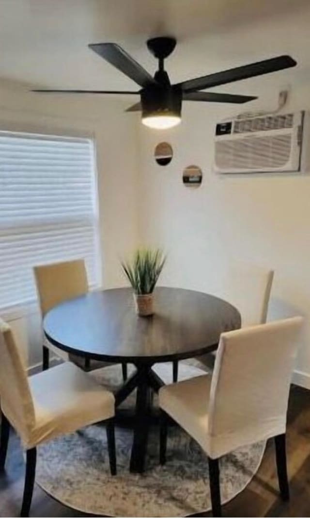 dining space featuring a wall unit AC, ceiling fan, and wood-type flooring