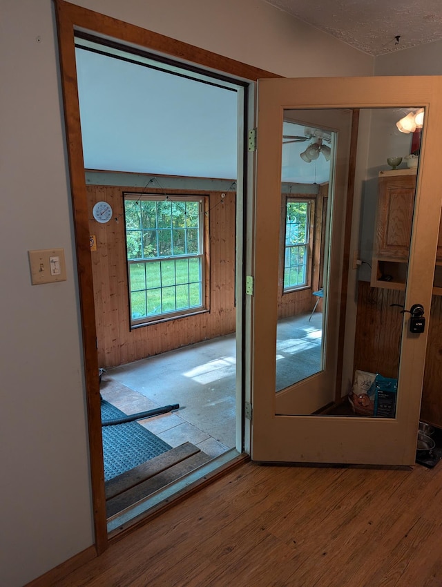 doorway to outside featuring ceiling fan, wood walls, light wood-type flooring, and a wealth of natural light