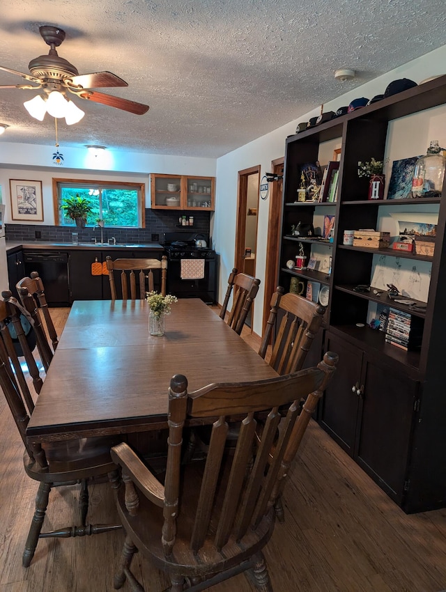 dining room with wood-type flooring, a textured ceiling, ceiling fan, and sink