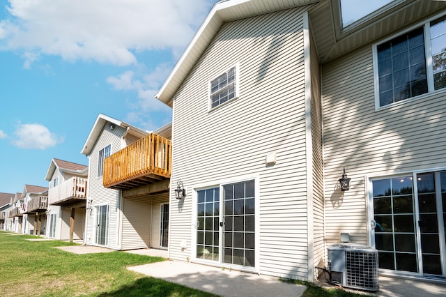 rear view of house featuring a yard, a balcony, and cooling unit