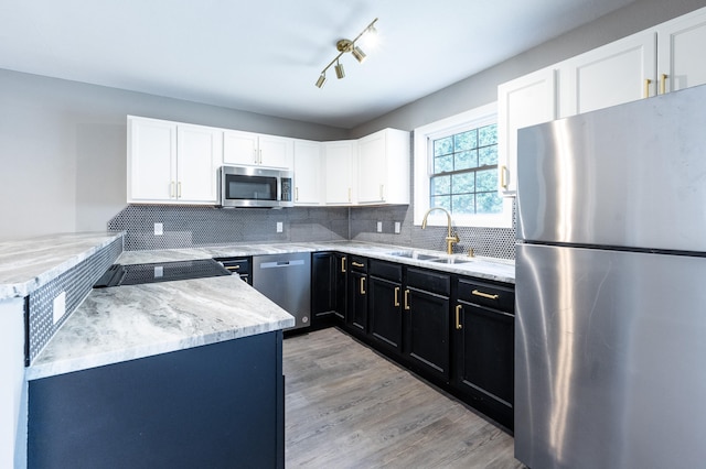 kitchen featuring white cabinetry, sink, backsplash, light hardwood / wood-style floors, and appliances with stainless steel finishes