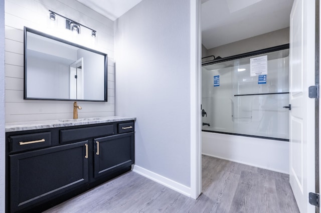 bathroom with shower / bath combination with glass door, wood-type flooring, and vanity