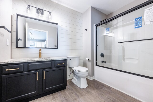 717 Tioga Park Unit 717, Big Rapids, MI 49307 - full bath with wood finished floors, vanity, toilet, shower / bath combination with glass door, and wooden walls