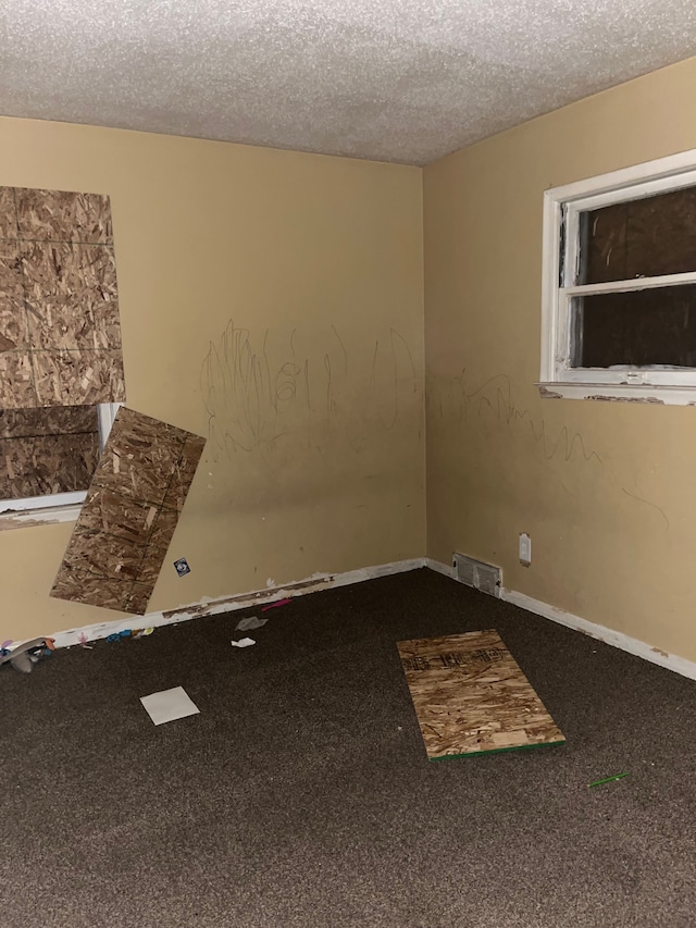 carpeted spare room with a textured ceiling