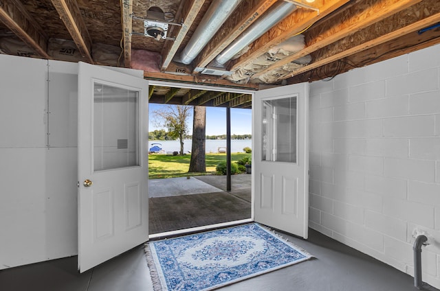 foyer entrance featuring finished concrete flooring, concrete block wall, and a water view