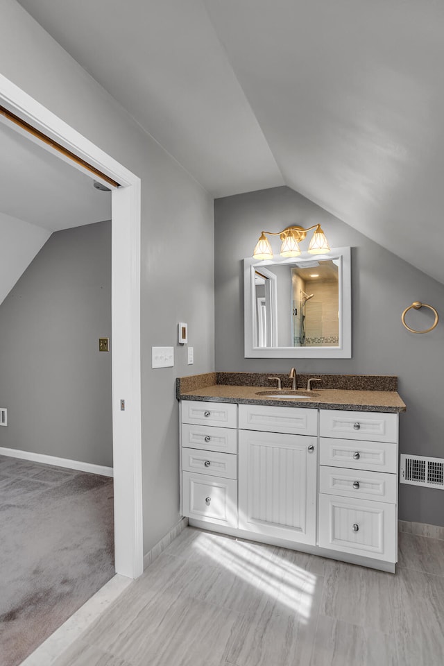 full bath featuring a shower, baseboards, lofted ceiling, and vanity