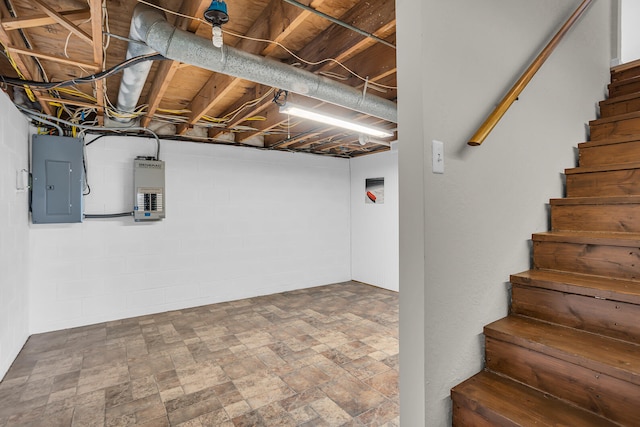 unfinished basement featuring electric panel and stairs