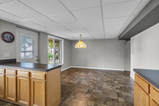 1620 Little Dr, Horton, MI 49246 - kitchen with dark countertops, baseboards, a paneled ceiling, a peninsula, and dark stone finish flooring