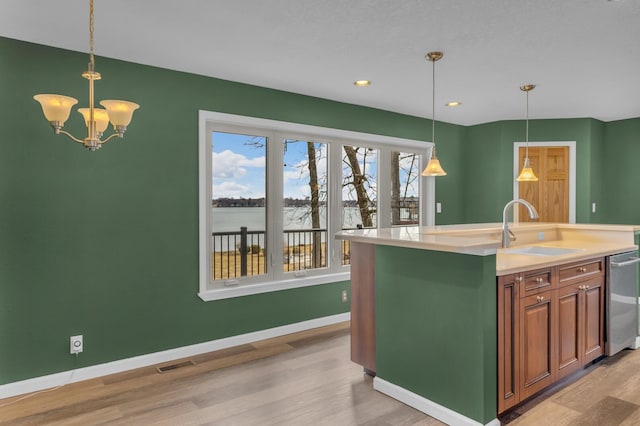 kitchen featuring baseboards, visible vents, light wood finished floors, a sink, and dishwasher