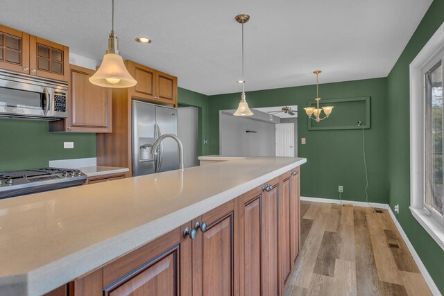 kitchen featuring light countertops, light wood-type flooring, brown cabinets, and stainless steel appliances