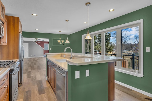 kitchen featuring light wood-style flooring, appliances with stainless steel finishes, light countertops, and a sink