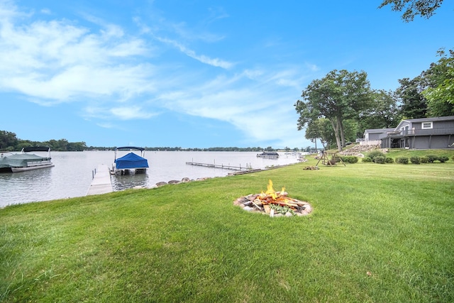 view of yard featuring an outdoor fire pit, a water view, and a boat dock