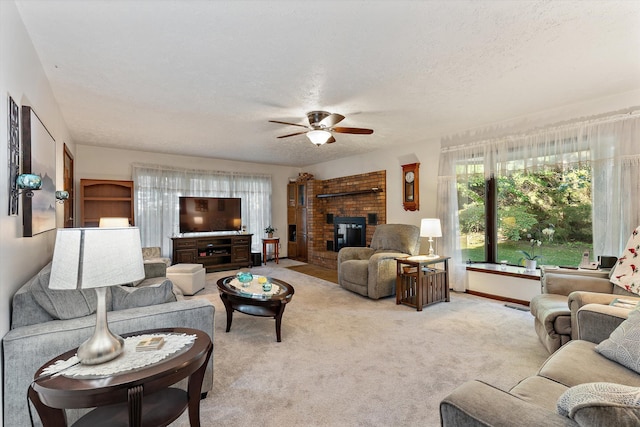 living room featuring a textured ceiling, ceiling fan, a fireplace, and light carpet