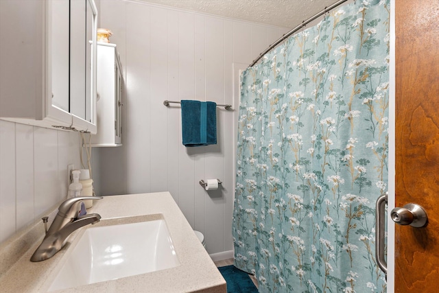 bathroom with a shower with curtain, wood walls, a textured ceiling, and vanity